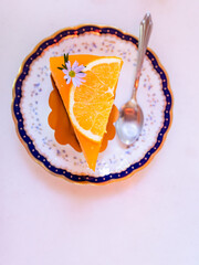 Top view of Orange cake on white table with spoon, flower topping