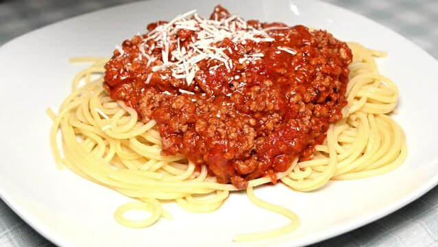 adding cheese to cooked spaghetti bolognese