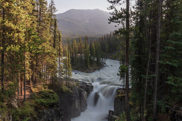 Sunwapta Falls in the stunning Canadian Rockies at sunrise in summertime with beautiful cascading waterfall in popular tourist, landscape area of Canada. 