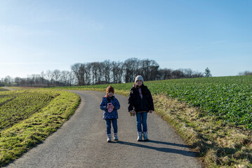 Two sisters walking on a country road in the countryside in spring