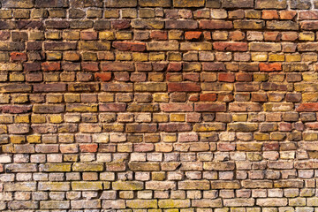 Wall with weathered, old bricks and partially washed out joints