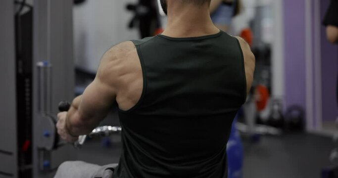 A man training back muscles on training apparatus at the gym