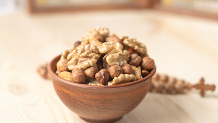 Various nuts in clay cup on table in front of Orthodox icon. Food for Christians during Lent, Lenten foods.