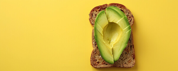 Sliced avocado on toasted whole-grain bread. Top down view on a sunny yellow background Top view space to copy