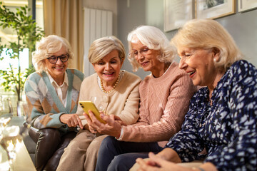 Group of senior women using smartphone together at home