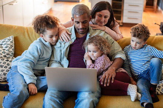 Family using laptop together at home on the couch