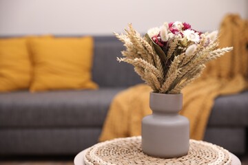 Obraz na płótnie Canvas Bouquet of beautiful dry flowers and spikelets in vase on side table at home. Space for text