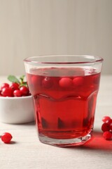 Tasty refreshing cranberry juice and fresh berries on light wooden table