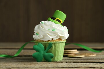 St. Patrick's day party. Tasty cupcake with green leprechaun hat topper on wooden table, closeup