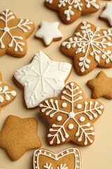 Tasty Christmas cookies with icing on beige background, closeup