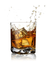 Whiskey splashing out of glass on white background
