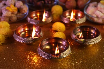 Diwali celebration. Diya lamps on shiny golden table, closeup