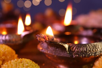 Diwali celebration. Diya lamps on table against blurred lights, closeup