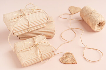 Craft paper recycled eco friendly gift boxes tied up with string bow on beige background with heart shaped decoration used for congratulation as holiday celebration present for birthday or wedding