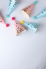 Beautiful party hats with pompoms on light background, top view. Space for text
