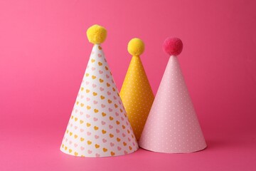 Beautiful party hats with pompoms on pink background