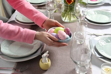 Woman setting table for festive Easter dinner at home, closeup