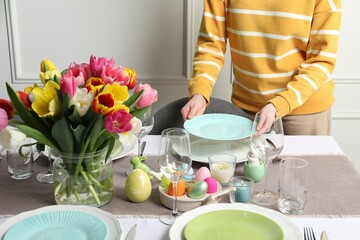 Woman setting table for festive Easter dinner at home, closeup