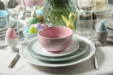 Easter celebration. Festive table setting with elegant dishware and painted eggs