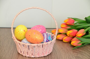 Easter, Easter egg color vibrant, spring Orthodox holiday. colorful decorated eggs in a pink basket. inscription happy easter, gift, red yellow tulips