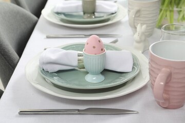 Easter celebration. Festive table setting with elegant dishware and painted eggs