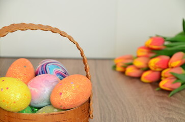Easter, Easter egg color vibrant, spring Orthodox holiday. colorful decorated eggs in a pink basket. inscription happy easter, gift, red yellow tulips