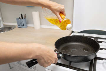 housewife pours sunflower oil into a frying pan