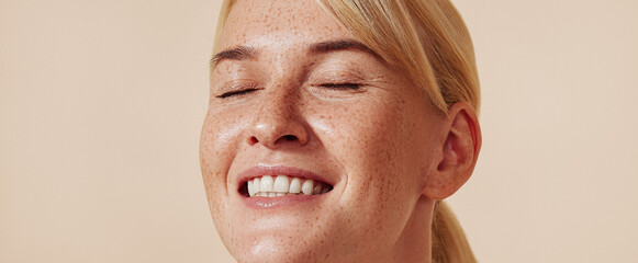 High-detailed portrait of a smiling female with freckles. Happy blond with closed eyes and freckled...
