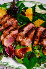 Fried duck breast in honey soy glaze with mixed salad and oranges.top veiw.