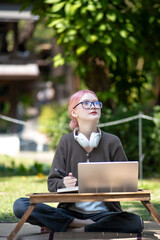 Woman working at the laptop in the backyard with a lot of greenery,  laptop and portrait of woman in park for education