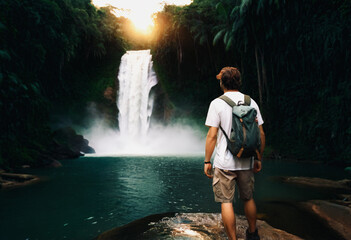 Persona observa cascada en selva tropical, ambiente sereno y majestuoso. - obrazy, fototapety, plakaty
