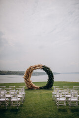 Fototapeta premium Decorations of a wedding ceremony on a green lawn. Grandiose large and stylish arch and chiavari chairs