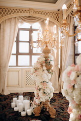 Wedding decoration with vintage crystal chandeliers with candles and white and pink flowers. Glass pendants in the form of balls. A light bulb in the shape of a candle.