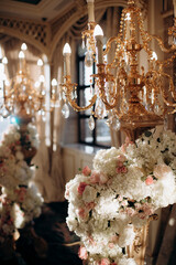 Wedding decoration with vintage crystal chandeliers with candles and white and pink flowers. Glass pendants in the form of balls. A light bulb in the shape of a candle.