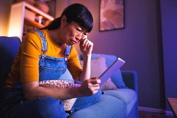 Woman reading sad movie review using tablet computer