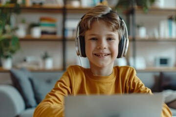 Young boy in yellow top using laptop with wireless headphones
