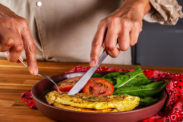 plate with an omelet and salad of sliced tomatoes and arugula