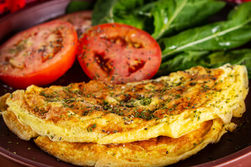 plate with an omelet and salad of sliced tomatoes and arugula