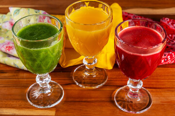 bowls with orange juices, kale with coconut water and apple, and beetroot with orange and carrot