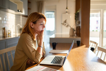 Woman working from home looking concerned at laptop screen