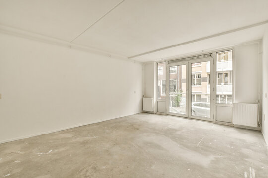 Empty white room with large windows and concrete floor