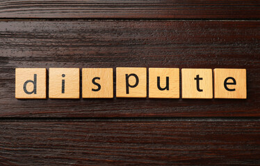 Squares with word Dispute on dark wooden table, top view