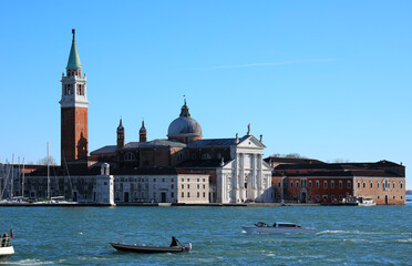 church and high bell tower of Saint George in Giudecca canal in Venice with many boats in Italy