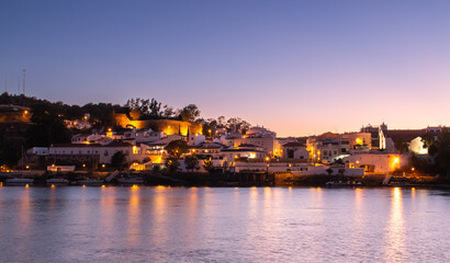 Fototapeta na wymiar Alcoutim un pequeño pueblo del Algarve en Portugal. Alcoutim al anochecer a orillas del río Guadiana. Casas blancas con las últimas luces del día y las farolas encendidas.
