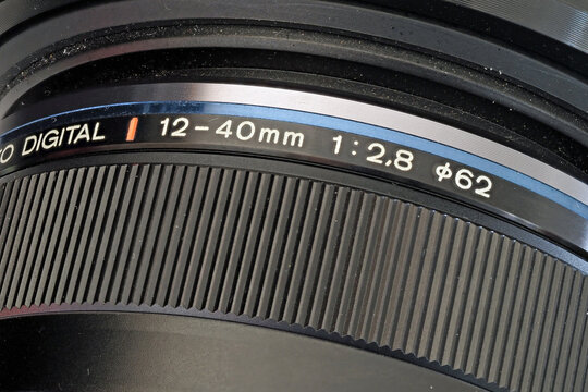 Close-up image of a black digital camera 12-40mm lens, showing the maximum aperture as F2.8 and the lens diameter of 62mm as well as the focusing ring