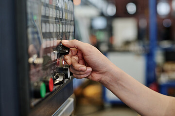Hand of unrecognizable female specialist working in factory operating CNC machine