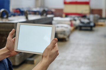 Selective focus shot of unrecognizable factory worker holding digital tablet with blank screen, copy space