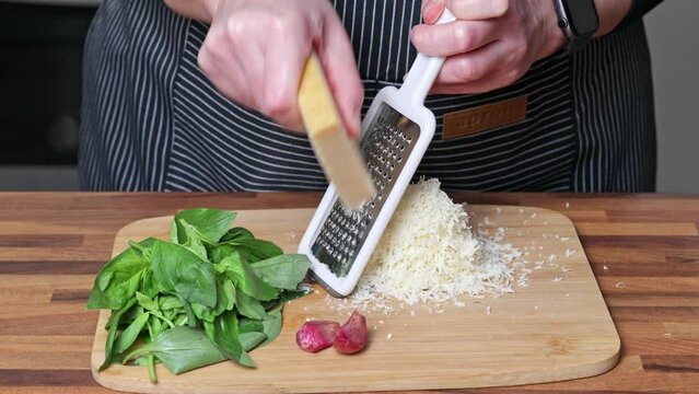 Cooking of pesto sauce. Woman hand close up grating parmesan cheese.