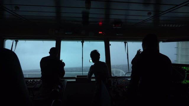 Storm at sea. People on captain's navigation bridge take photos of high waves. Strong pitching,