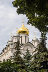 Fototapeta na wymiar Cathedral of the Archangel Michael behind green trees. Summer in Moscow Kremlin garden.